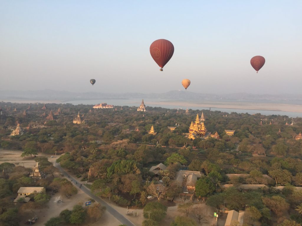 Hot air balloons floating toward the Irrawaddy River in the background with Shwezigon Pagoda (Paya) in front, Bagan, Myanmar