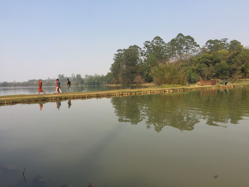 Three people crossing a lake while walking on a narrow strip of land