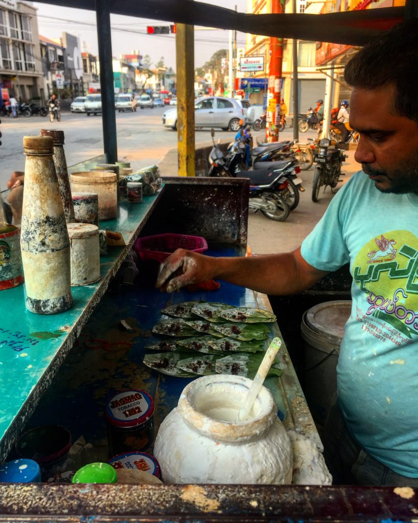 Man making betel nut packets from a street cart