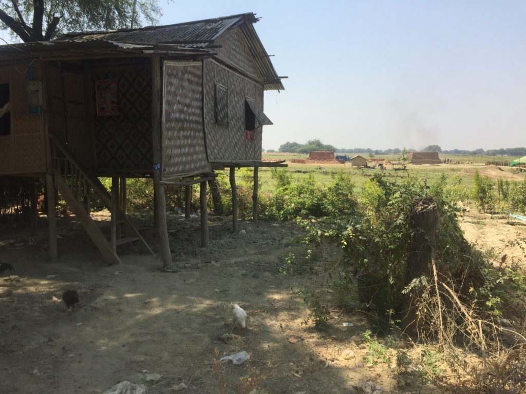 Bamboo and wood home on stilts beside the dry bed of the Irrawaddy River