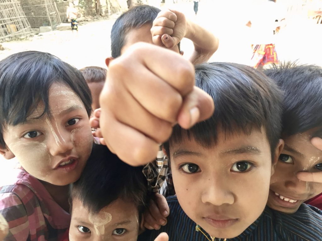 Close up photo of six young children smiling and mugging for the camera