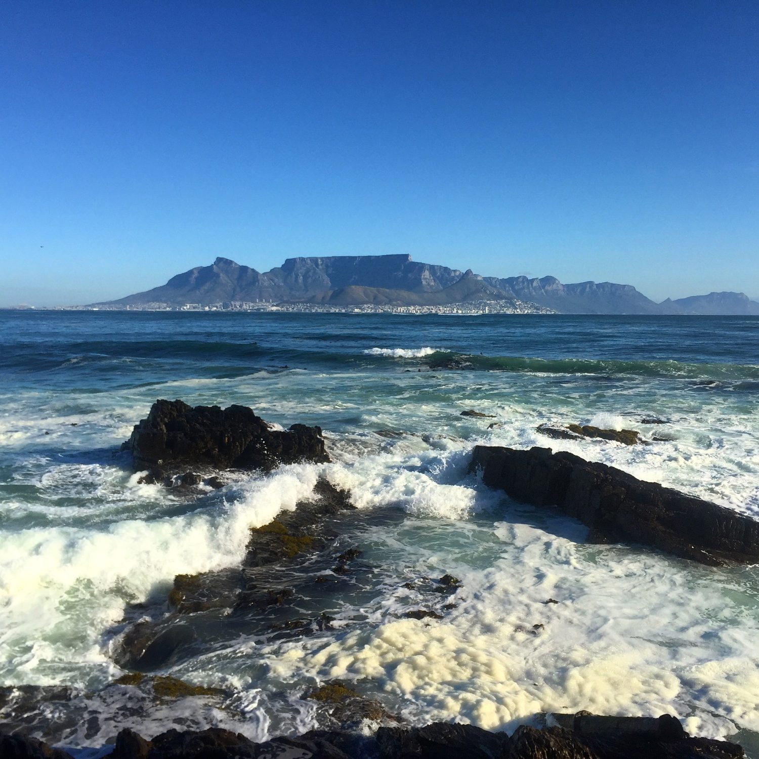 View of Table Mountain from the shore with waves and foam washing up