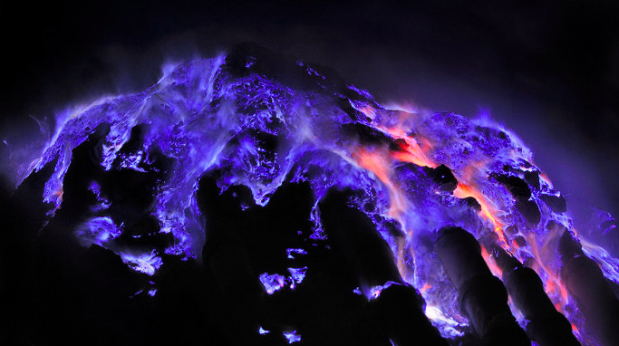 Blue lava flows down the darkened slopes of Kawah Ijen volcano, Java, Indonesia