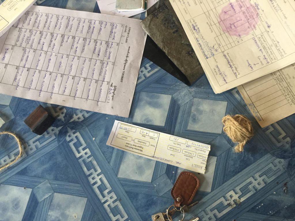 Overhead picture of train tickets and ticket list as staff writes out tickets for the following day's trip across the Goteik Viaduct