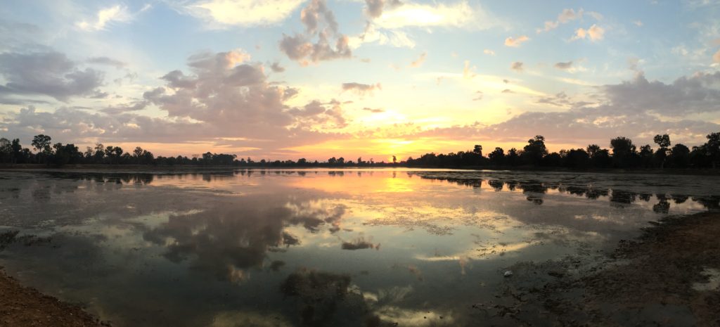 Panorama of sunrise and dappled clouds reflected in a lake