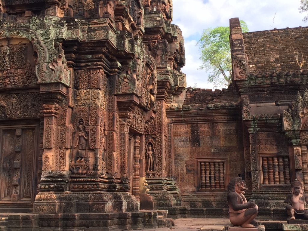 Intricate carvings and statuary in front of a massive red stone temple