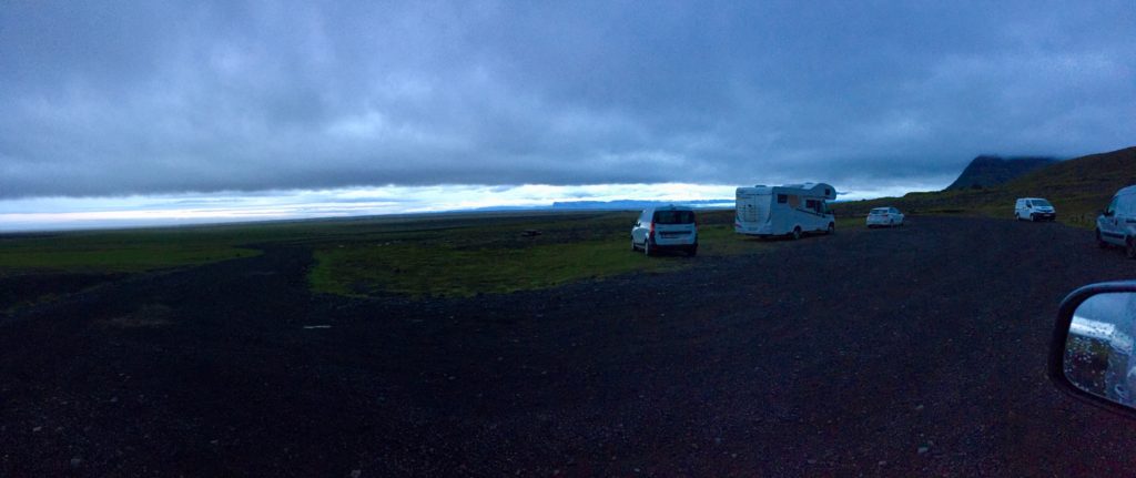 A few campers parked in a lot against a dramatic cloudy sky background