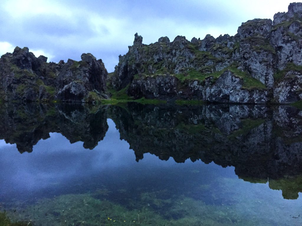 Mirror effect at Djupolon lagoon with rock formations reflected in the still water