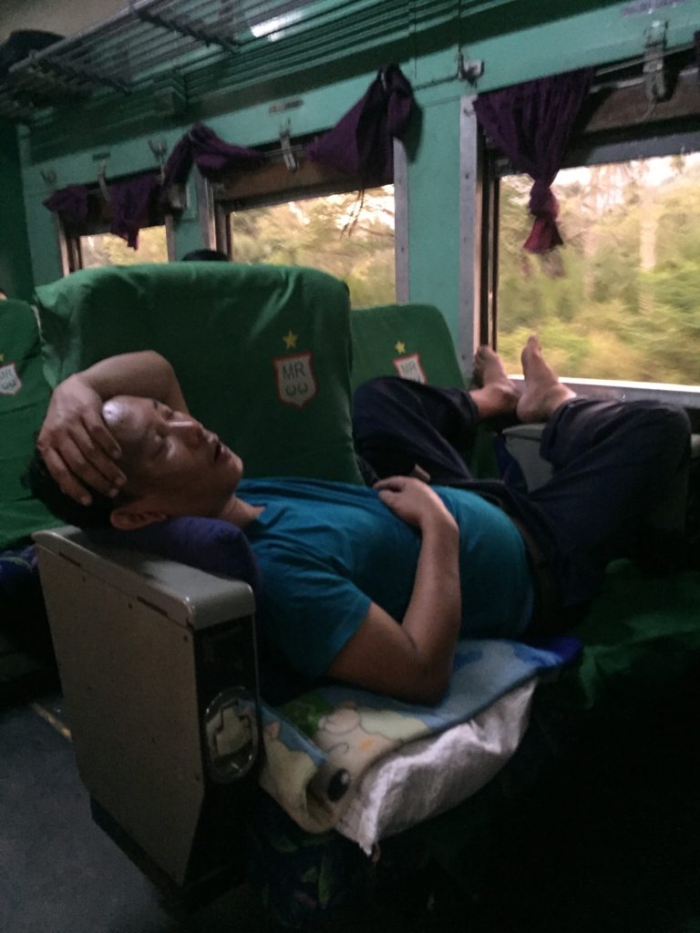 Sleeping man sprawled across two seats on the train to Mawlamyine