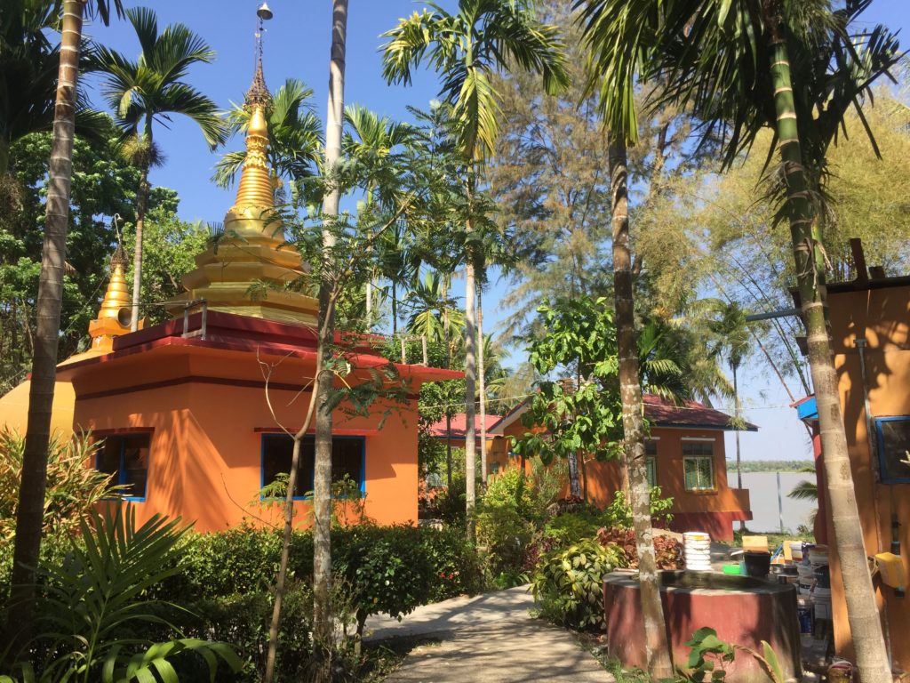 Palm trees and an orange building with golden spire atop on Shampoo Island (Gaung Se Kyun)
