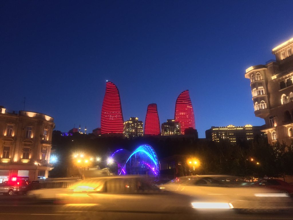 Three lit-up red buildings tower over Baku's nighttime skyline