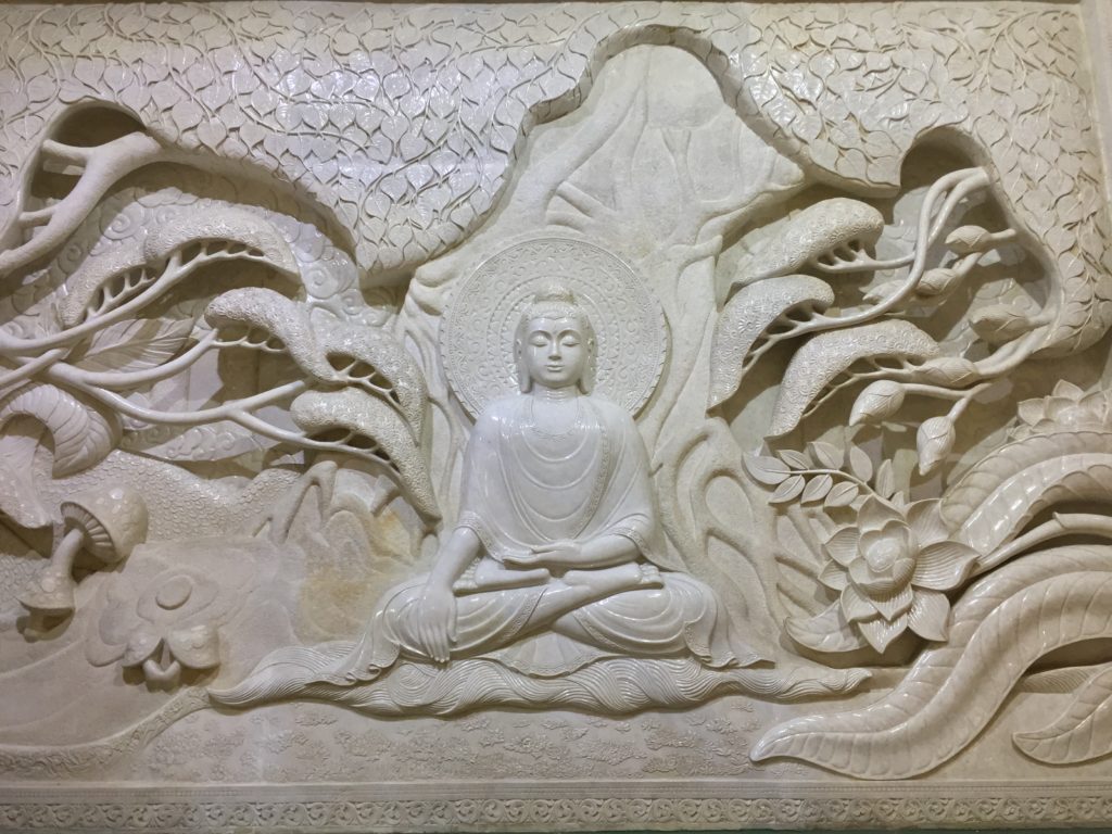 Intricately carved stone mural depicting a scene from the life of the Buddha
