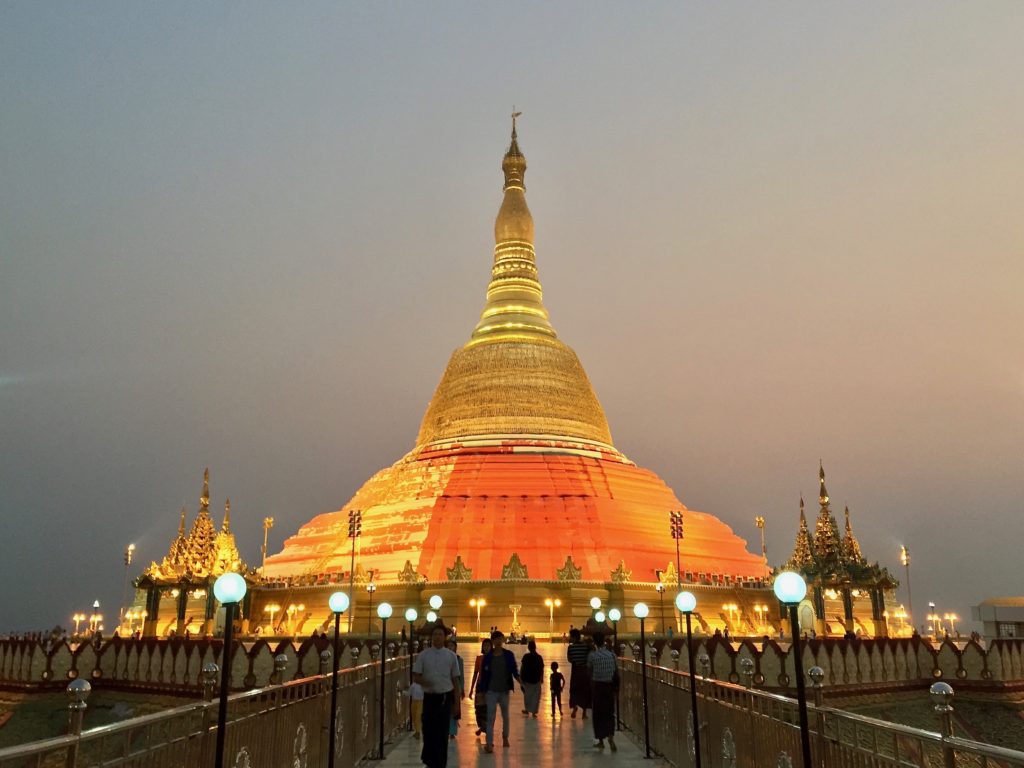 The gold and orange stupa of Uppatasanti Pagoda in the middle of a dusky evening sky