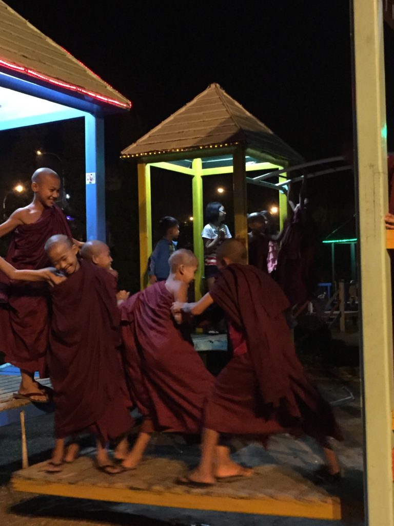 Novice monks in maroon robes play around on a playground in Naypyidaw's Water Fountain Garden