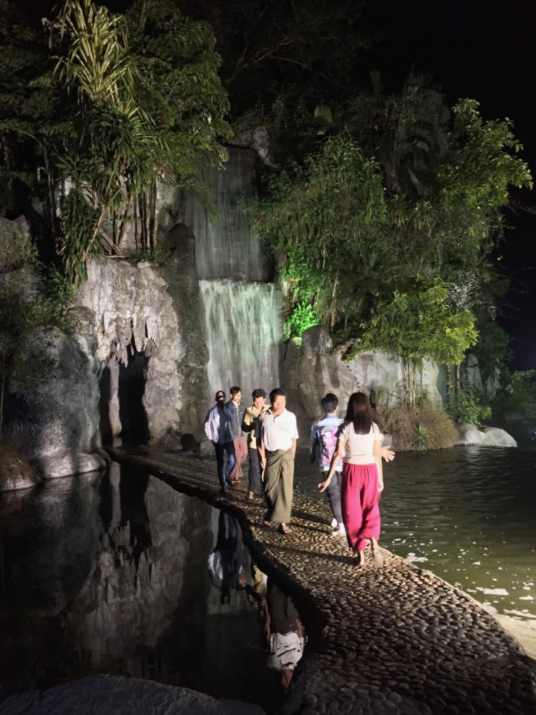 Locals walk across a walkway to an artificial waterfall in Naypyidaw's Water Fountain Garden