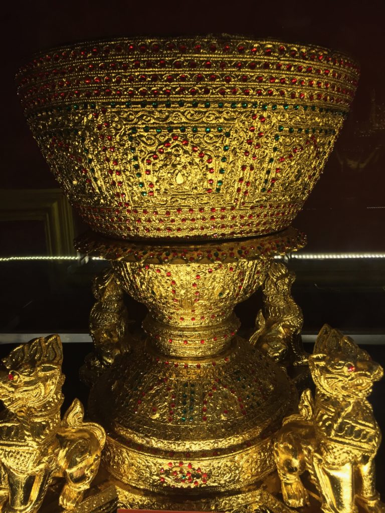 Golden betel nut spittoon with red and green jewels encrusted around the outside