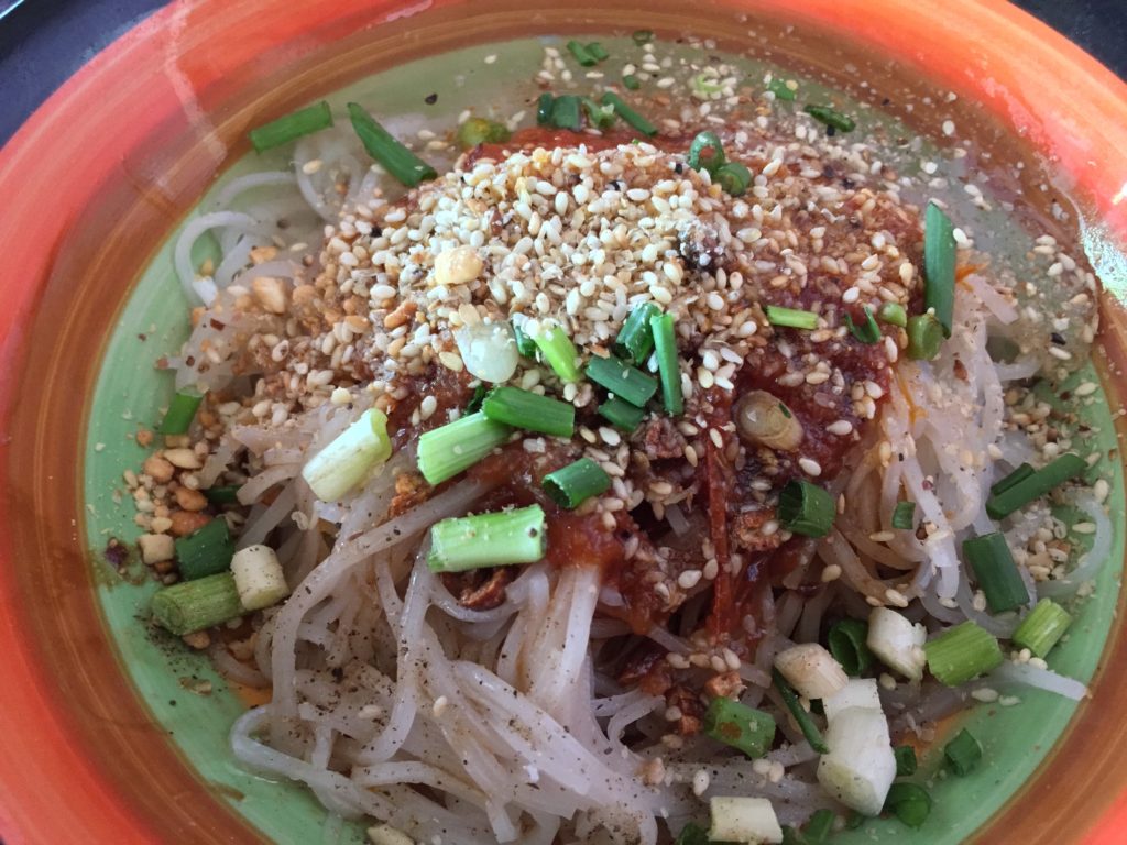 A bowl of Shan noodles sprinkled with green onions