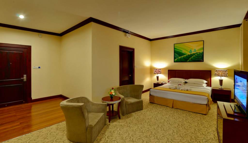 Large, nicely decorated hotel room with sitting area, queen size bed and flat screen television